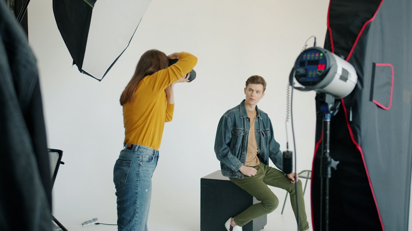 Fotograf dirigiert ein männliches Model bei einem Studio-Fotoshooting.