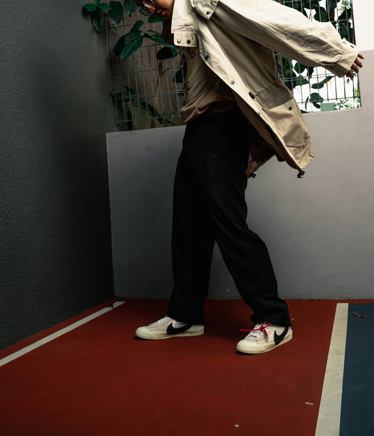Person in beiger Jacke steht auf einem bemalten Basketballplatz.